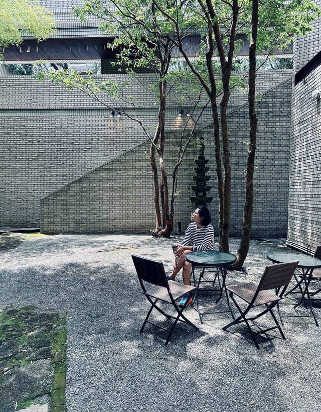 A woman sitting quietly outdoors, looking up in thought